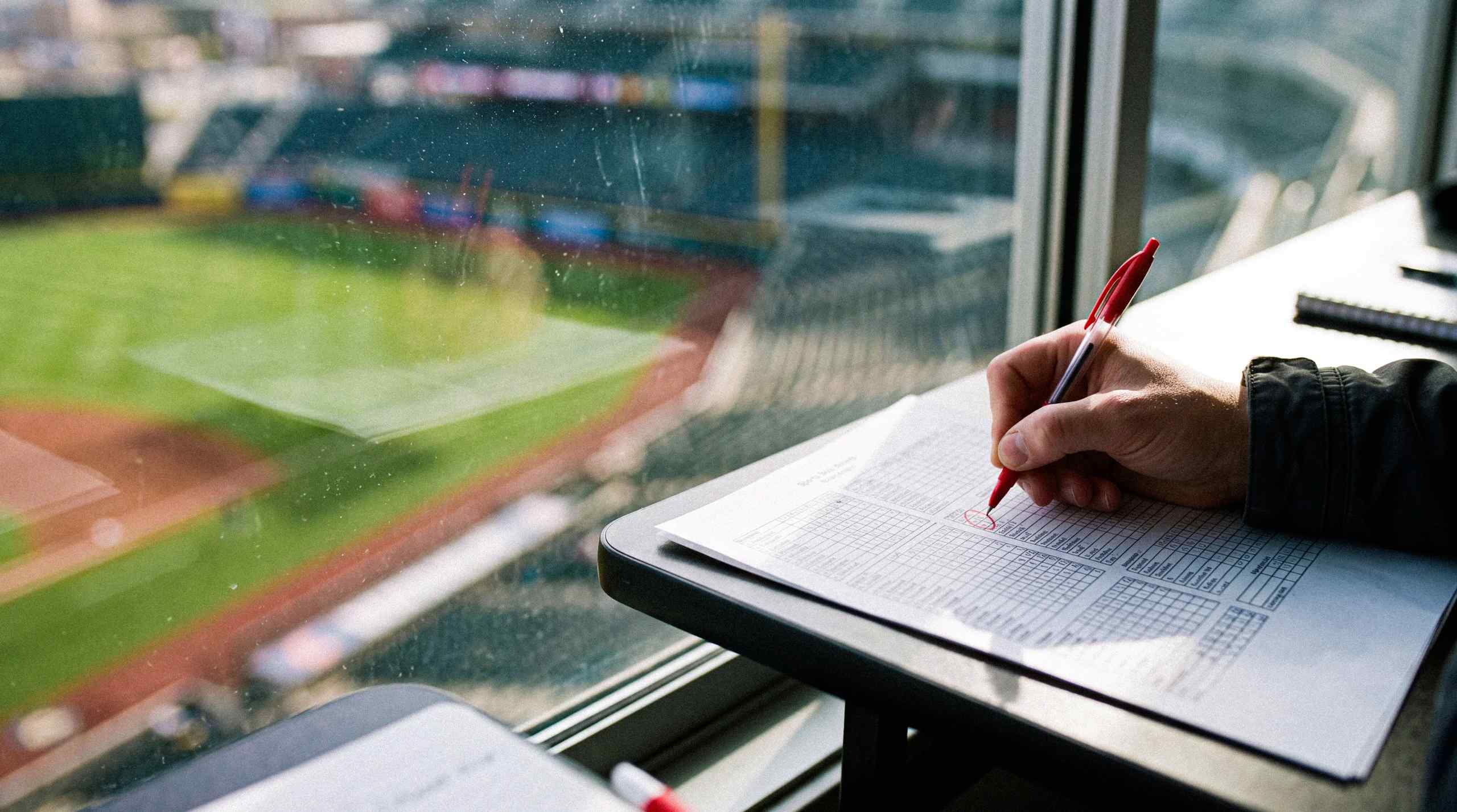 Watching a baseball game and taking notes.